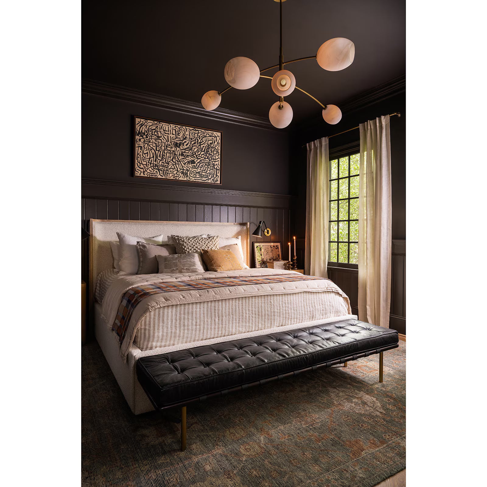 Modern bedroom with a bed, black upholstered bench, and decorative lighting fixture.