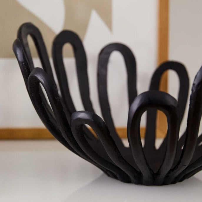 Black decorative bowl with a unique design on a white surface.