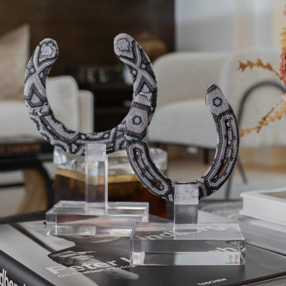 Decorative black and white beaded headpiece on a clear stand with a blurred indoor background