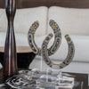 Decorative horseshoe sculpture on a stand with a candle and book in the background