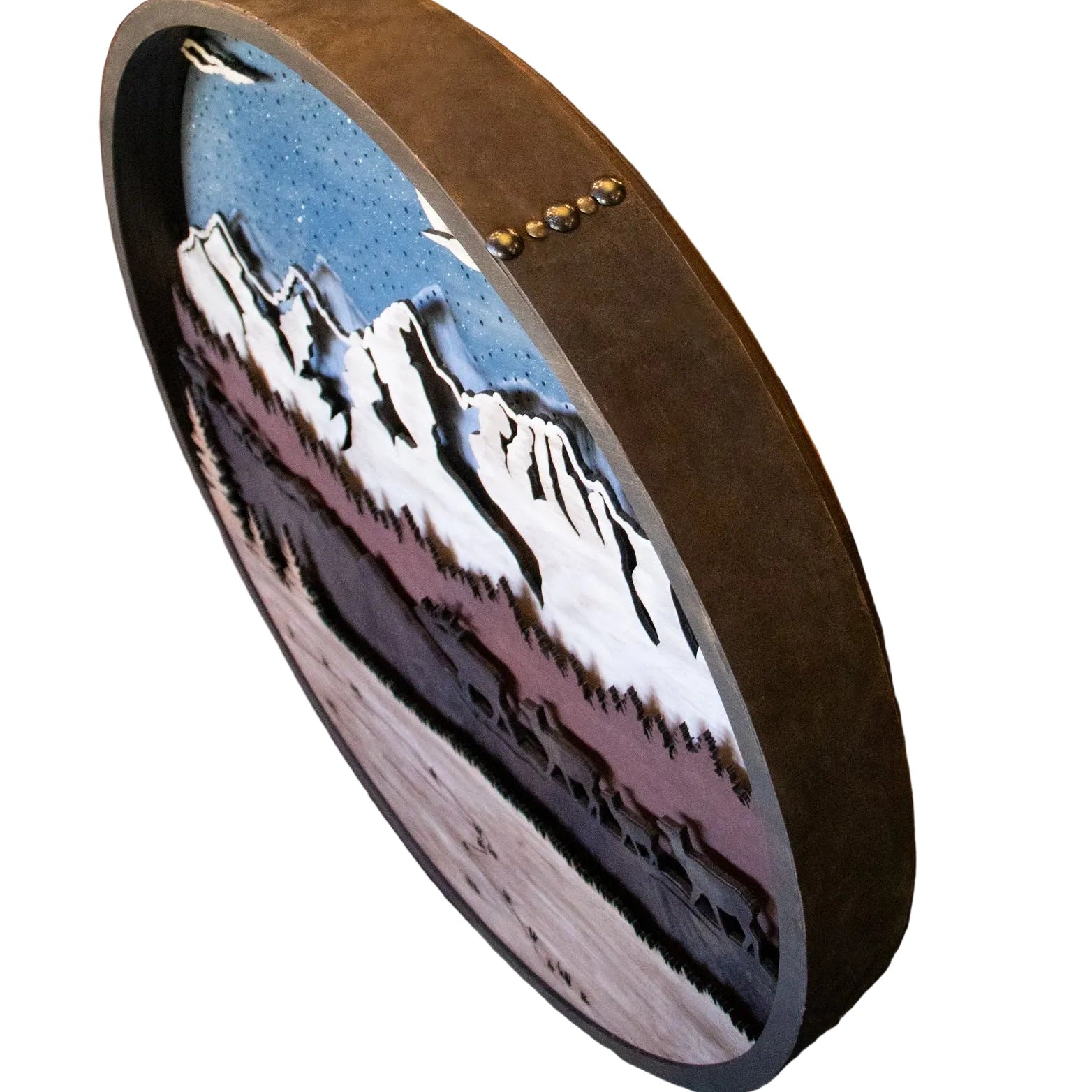 Round decorative item with mountain design on a wooden surface
