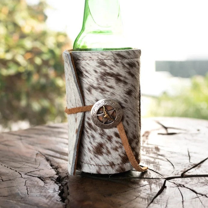 Green bottle in a cowhide bottle holder on a wooden surface with a blurred natural background