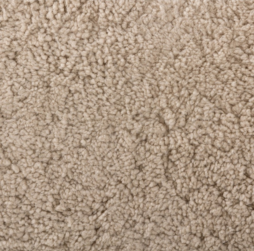 A close-up texture shot of a beige loop pile carpet, showing the dense, high-pile tufted fibers.