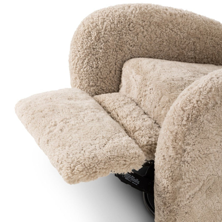 Close-up of a plush, high-pile textured recliner chair in a warm beige or cream color, with the footrest extended, set against a plain white background.