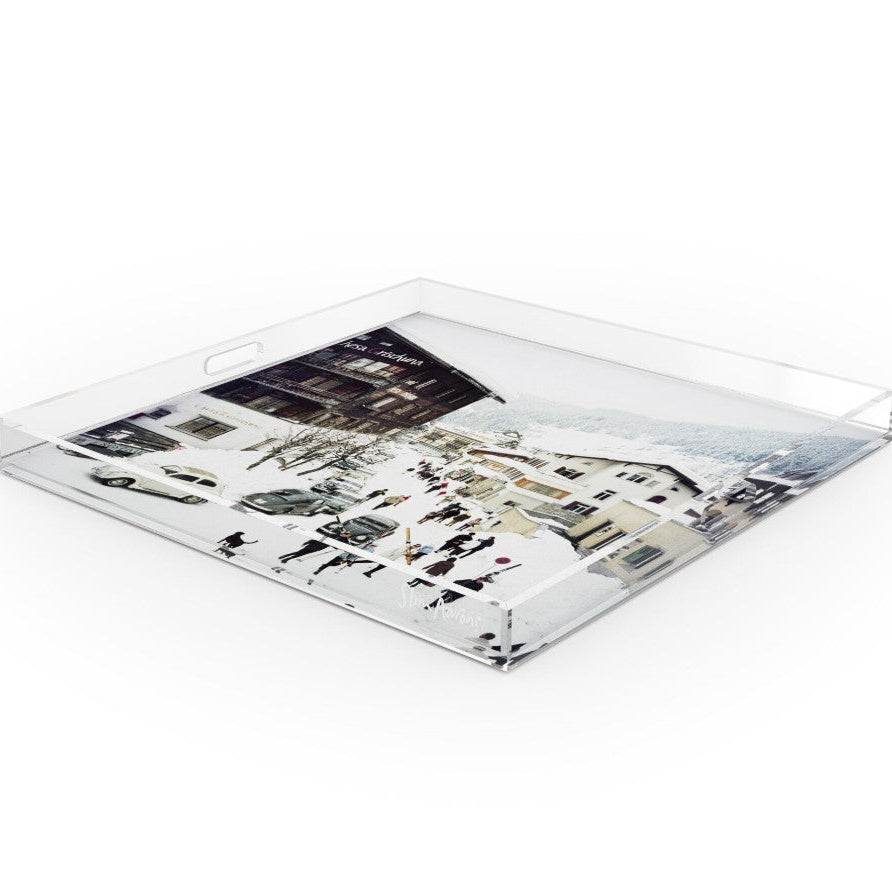 A square clear acrylic serving tray with integrated handles and a printed winter village scene on the bottom, shown on a plain white background.