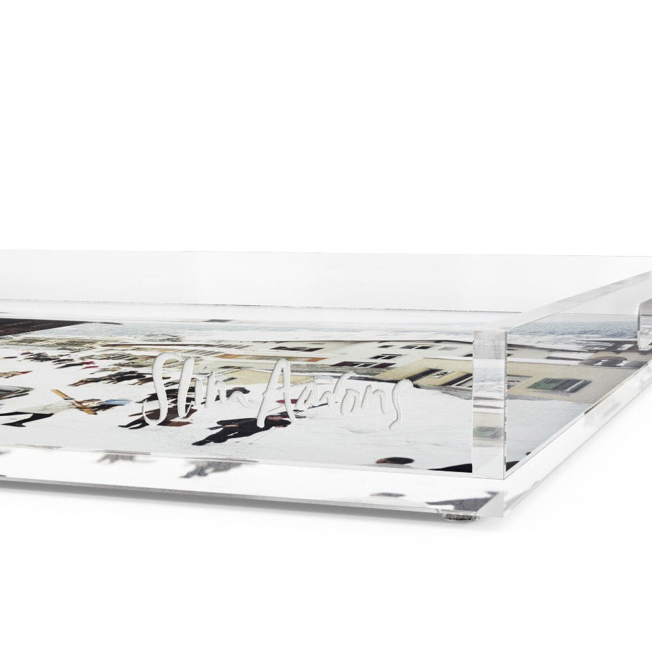 A clear acrylic or glass tray with a printed black-and-white cityscape design and the cursive brand name 'Shin Atrus' etched across the front, shown on a white background.
