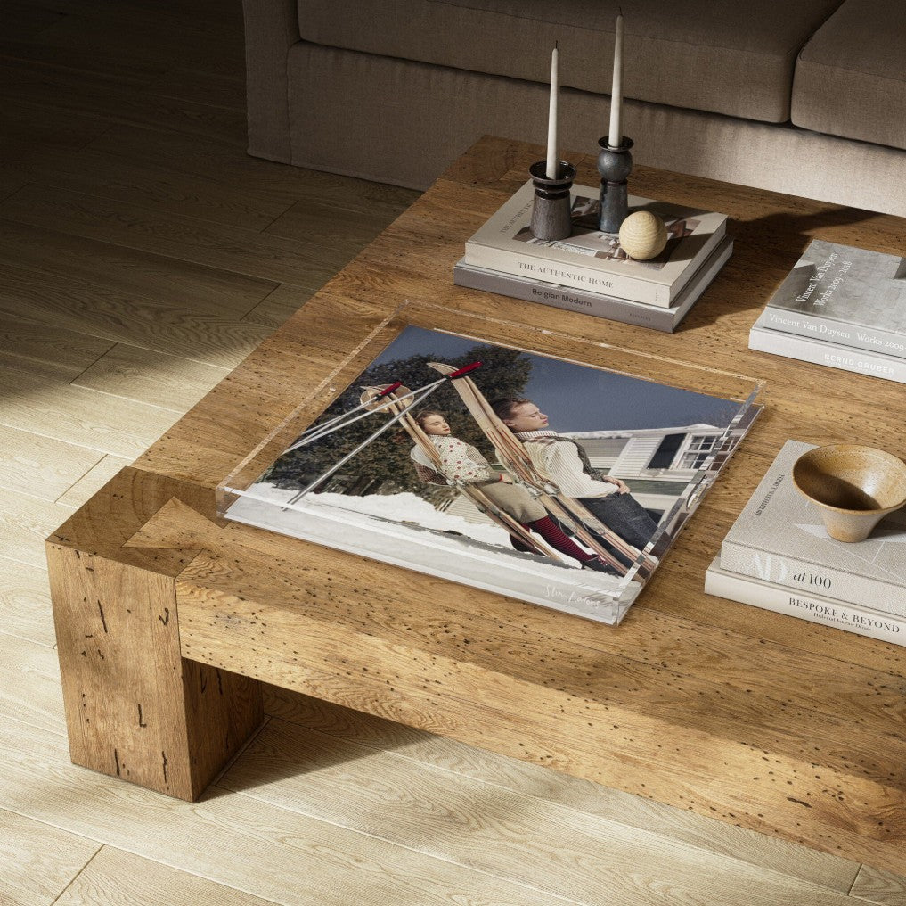 Wooden coffee table with books and a photo album on a wooden floor.