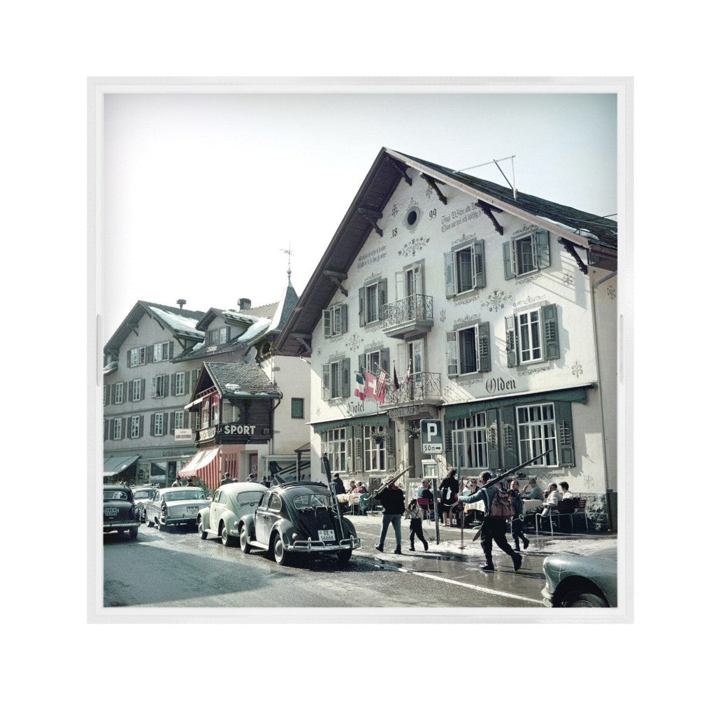 Vintage street scene with cars and people in a town square.