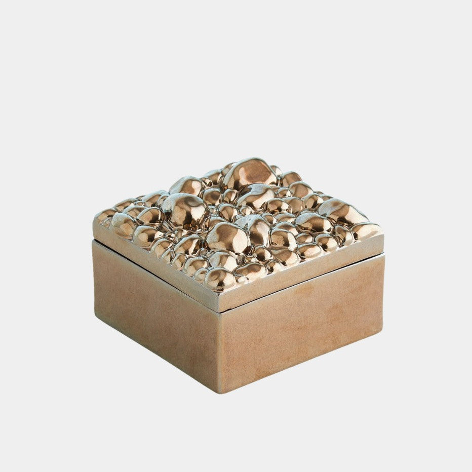 Decorative gold box with textured top on a light gray background
