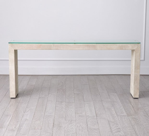 Modern dining table with glass top and wooden base on a light wood floor.