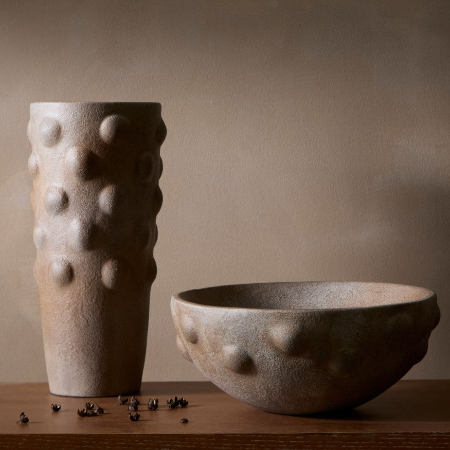 Two textured ceramic vases on a wooden surface with a neutral background