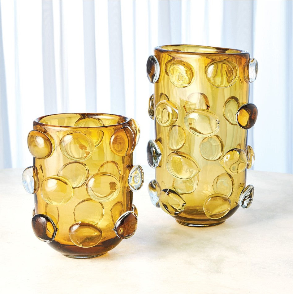 Two amber glass vases with bubble-like designs on a white surface.