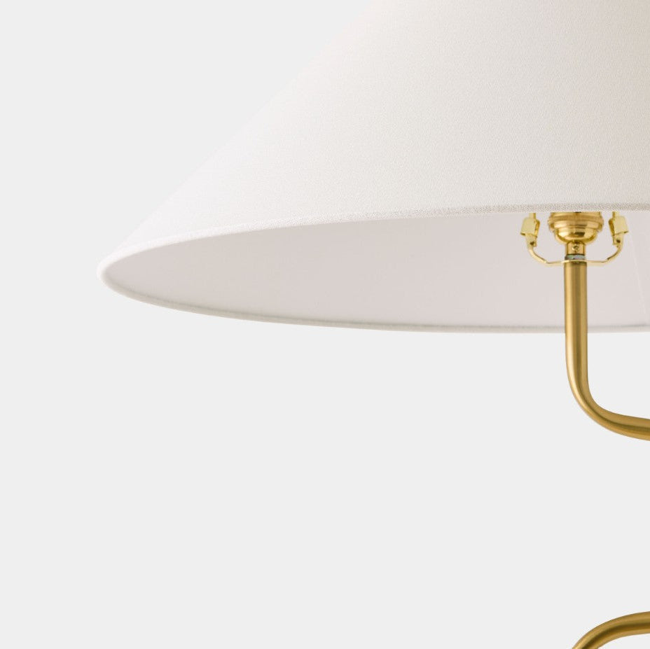 Close-up of a lamp with a white shade and gold fixture on a white background