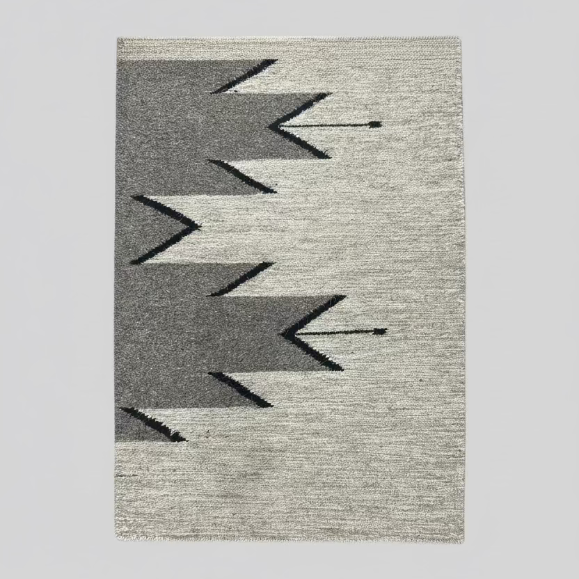 Gray area rug with black arrow pattern on a wooden floor