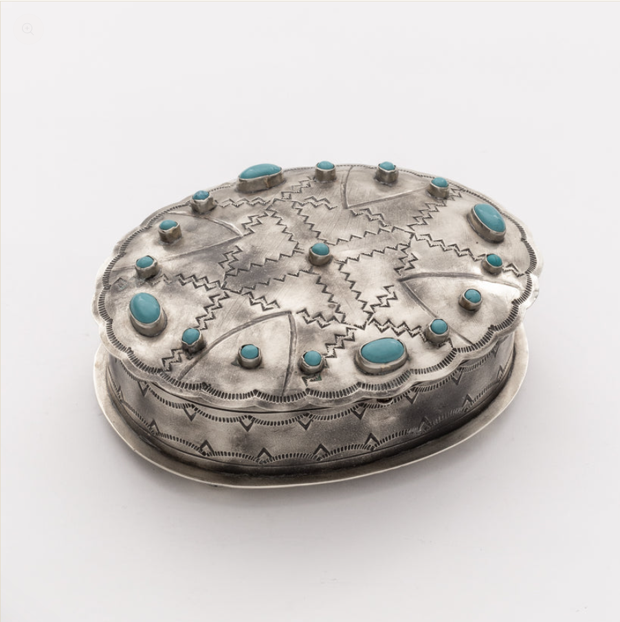 A round sterling silver box with a lid, decorated with geometric engraved patterns and set with multiple turquoise stones, shown on a plain white background.