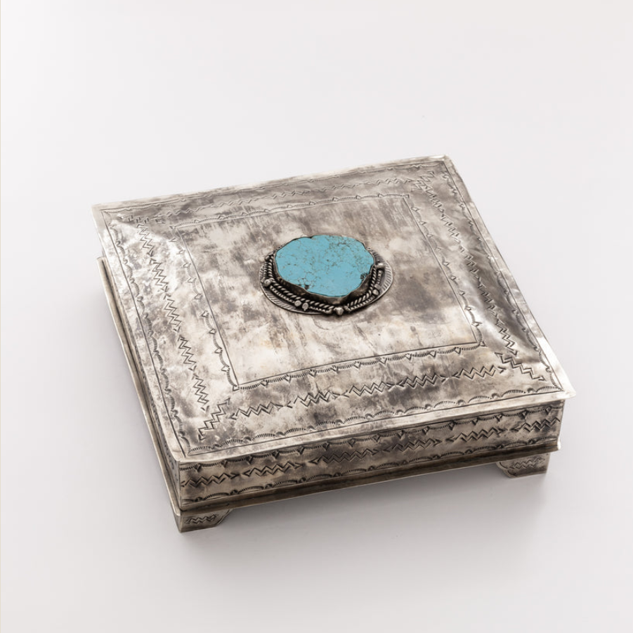 A square sterling silver jewelry box with engraved geometric patterns and a central round turquoise stone on the lid, photographed on a clean white background.