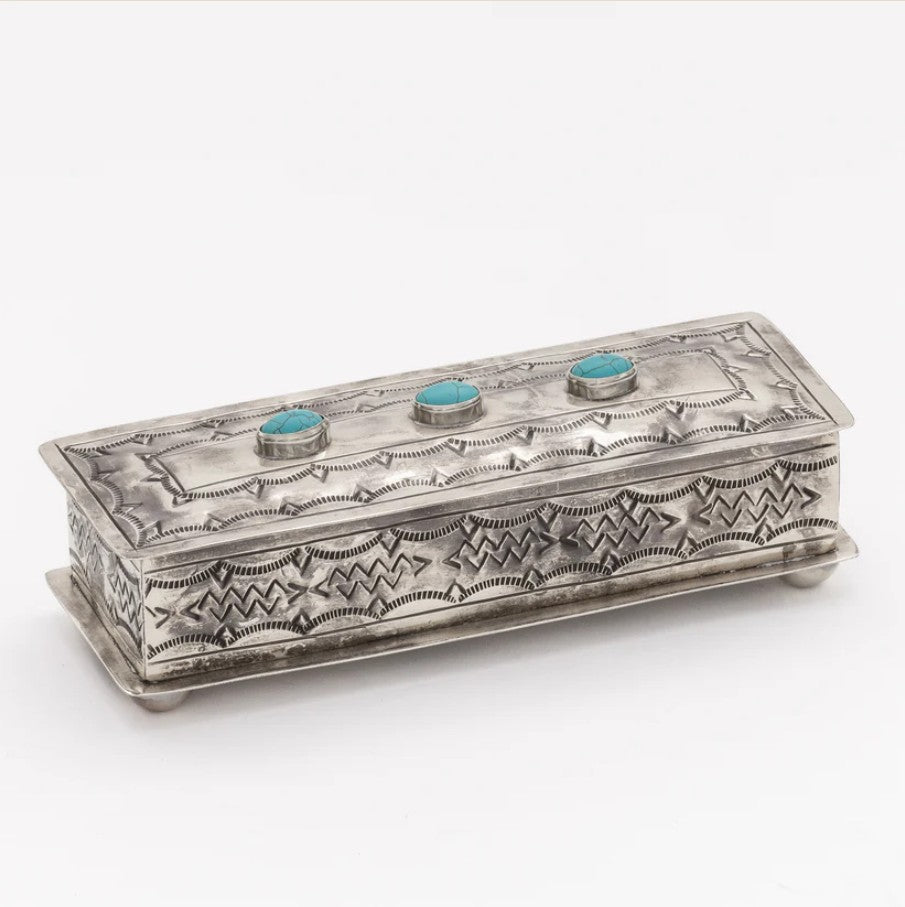 An ornate rectangular silver box with engraved geometric patterns and three turquoise stone accents on the lid, shown on a plain white background.