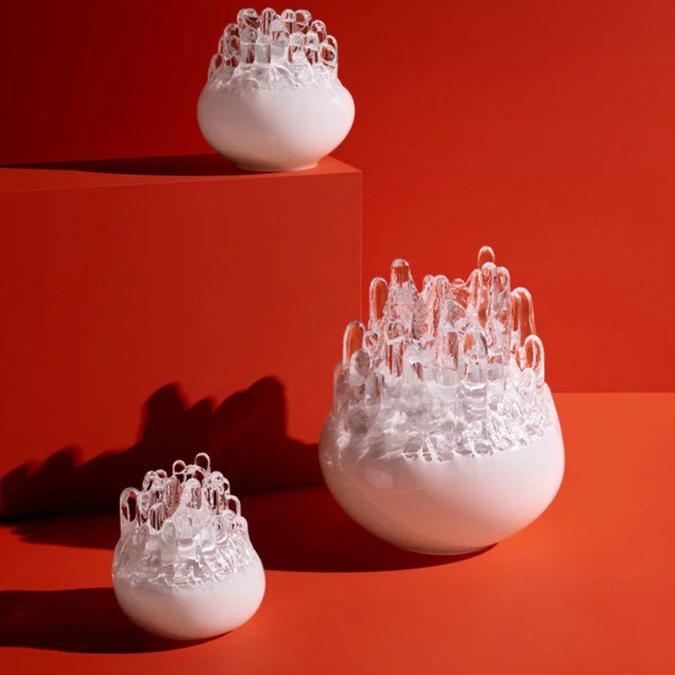Three white textured vases on a red platform with a red background