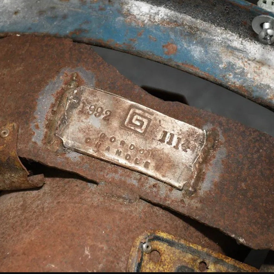 Close-up of a rusted metal mechanical part with a stamped plate reading '1989 GILDAN OIL CHANGE FILTER' and 'OIL CHANGE FILTER'.