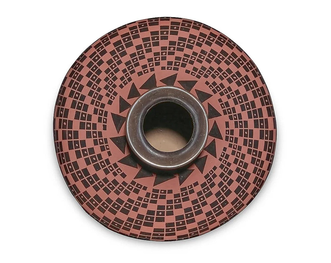 A circular ceramic wall-mounted planter or candle holder with a geometric pattern of black squares and triangles on a terracotta-colored background, featuring a central metallic rim and a dark opening.