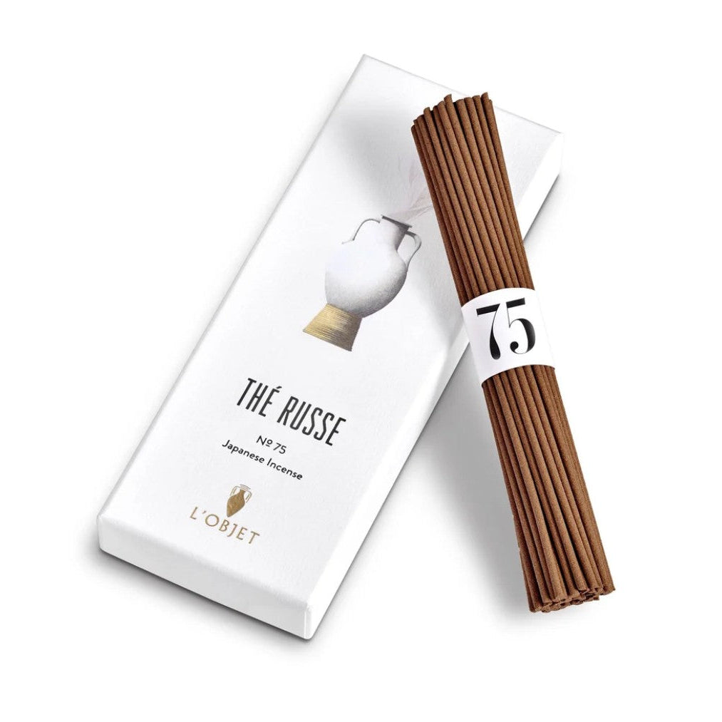 A bundle of dark brown Japanese incense sticks wrapped with a white paper band marked '75', displayed next to its white packaging box labeled 'THÉ RUSSE' and 'L'OBJET' on a clean white background.