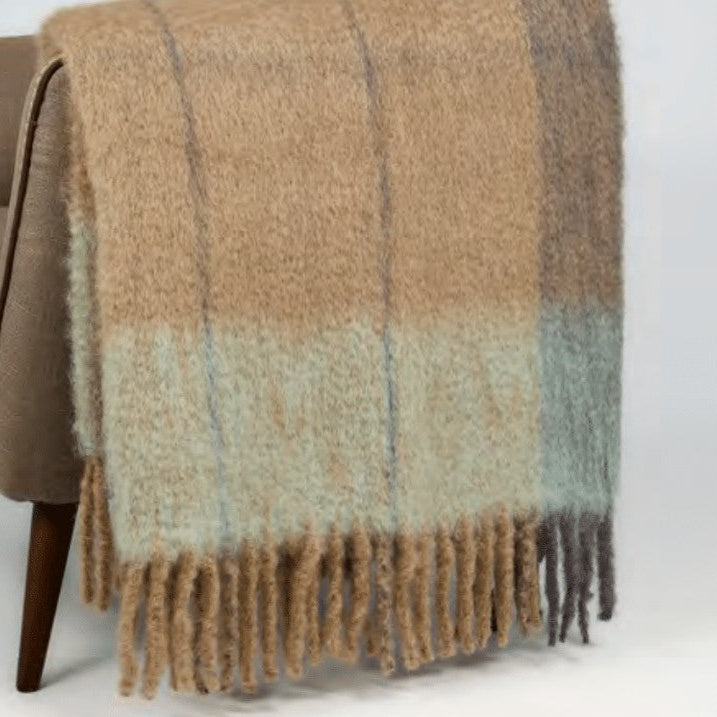 Brown plaid blanket draped over a brown armchair on a white background