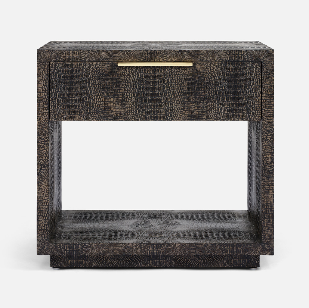 A modern side table with a dark textured crocodile skin pattern, featuring a single drawer with a slim gold pull handle and an open lower shelf, photographed against a clean white background.