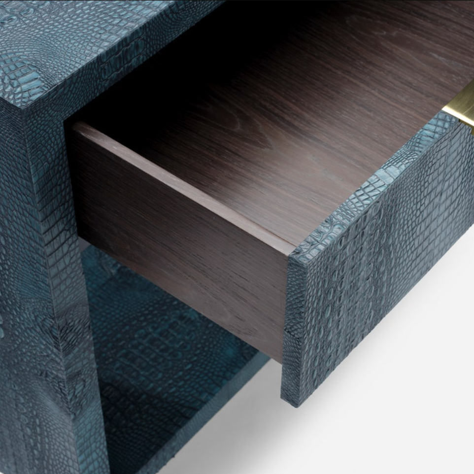 Close-up of a dark wood drawer pulled open from a textured teal blue cabinet with a reptile or crocodile skin pattern, showing a gold pull handle accent.