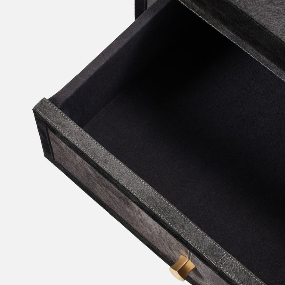 Close-up of an open drawer with a dark charcoal textured exterior, black fabric lining, and a small gold pull handle on a light gray background.