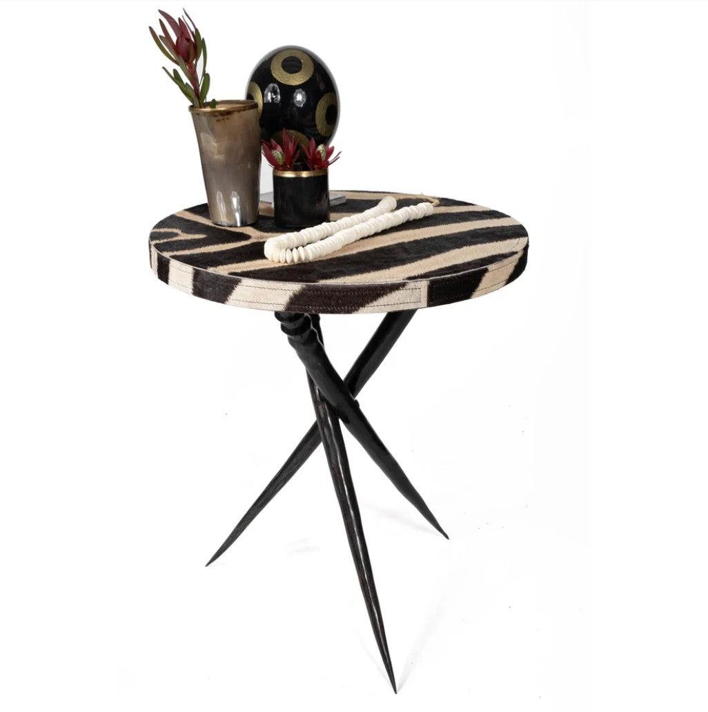 Small round table with zebra print top and black legs on a white background