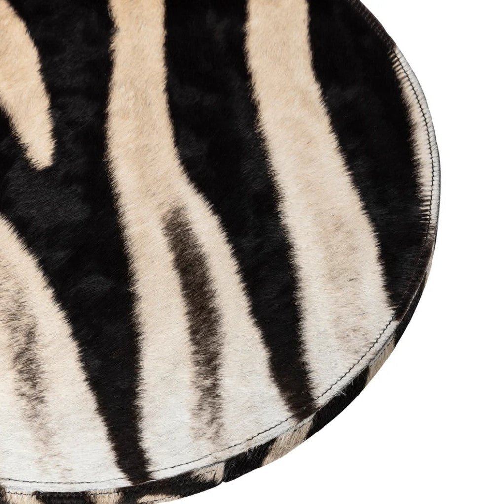 Round zebra print rug with black and beige stripes on a white background