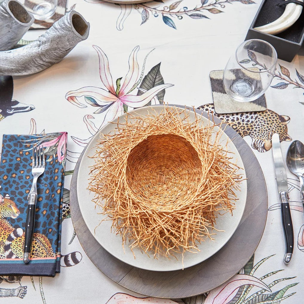 Dining table setting with a decorative plate, cutlery, and floral tablecloth.