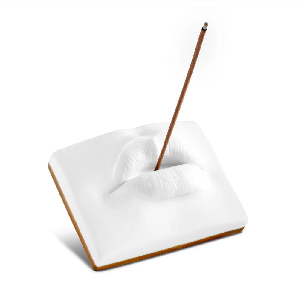 A square white ceramic incense holder shaped like lips with a single incense stick inserted, shown on a clean white background.