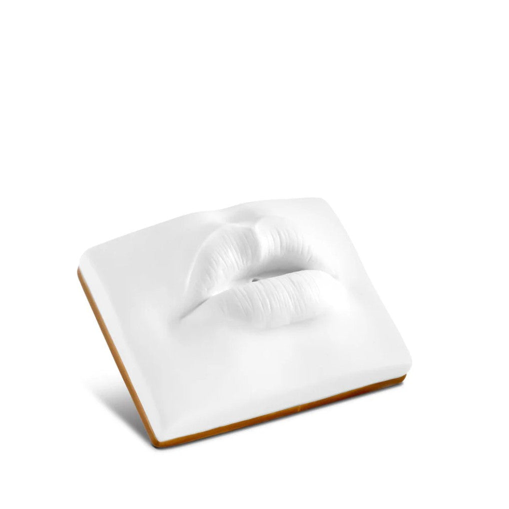 A square white cosmetic sponge with a sculpted 3D lip design on the top surface, shown on a plain white background.