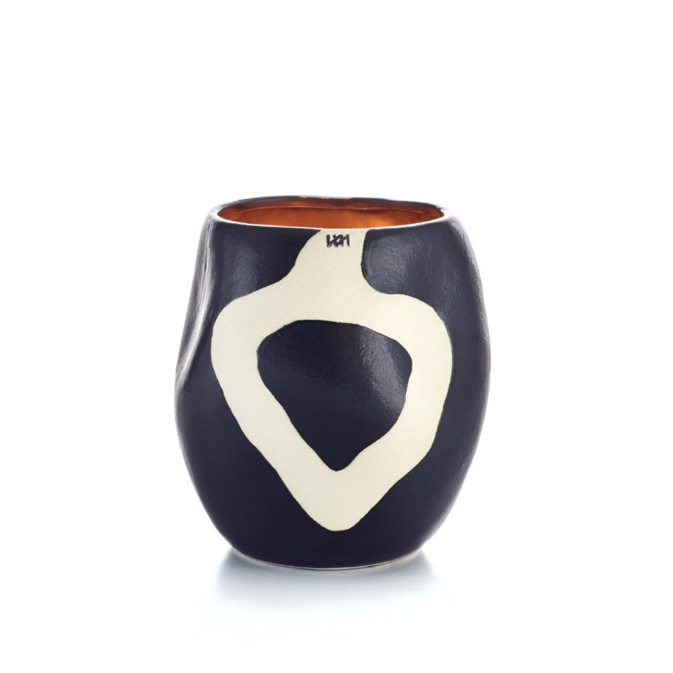 A small ceramic cup with a dark navy blue exterior, a large cream-colored abstract heart-shaped pattern on the front, and a warm terracotta-colored interior, shown on a white background.