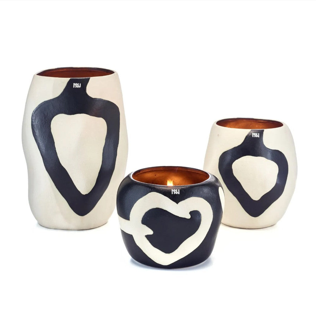 Three ceramic candle holders with a black and white abstract heart pattern and a warm copper interior, displayed on a white background.
