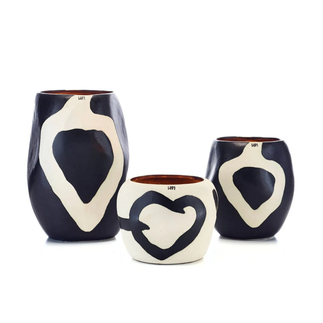 Three ceramic vases with abstract white heart-like shapes on a glossy black glaze, displayed against a plain white background.
