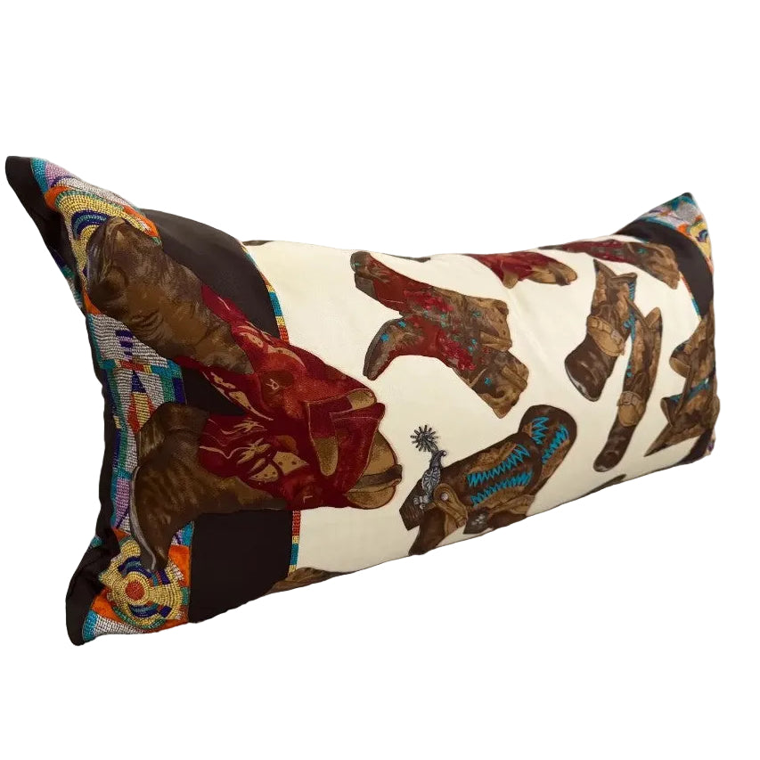 A long rectangular lumbar pillow with a western boot print, resting on a light gray fabric sofa.