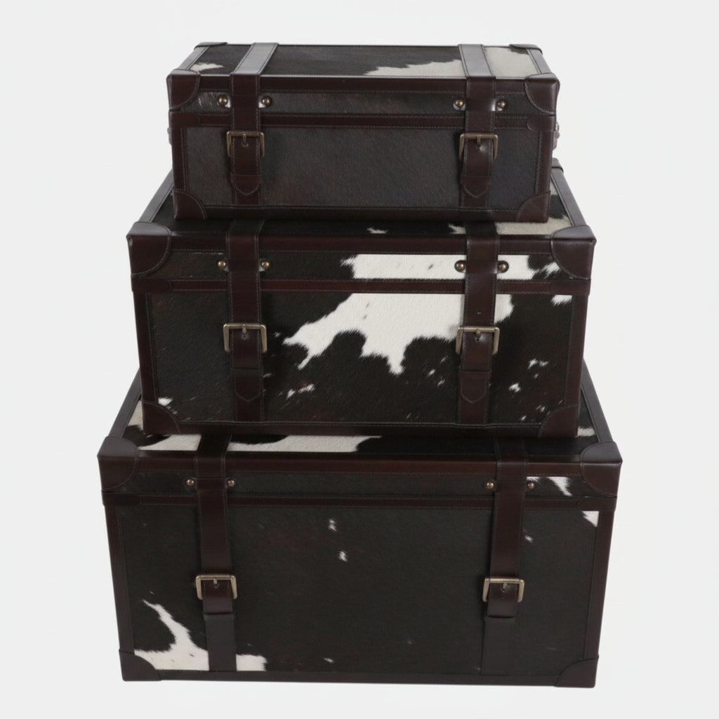 Set of three black leather storage trunks with cowhide pattern on a white background