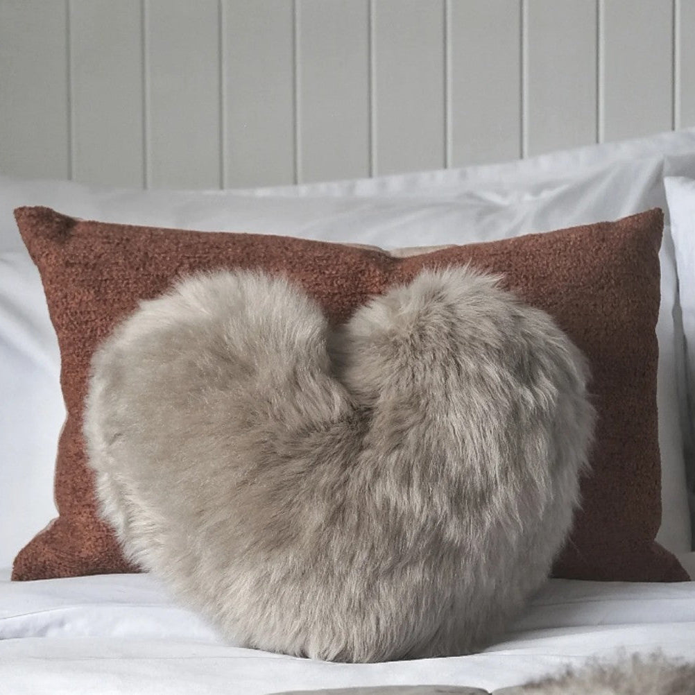 Decorative pillow with fur heart on a bed