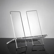 Clear acrylic display stand on a reflective surface with a gray background