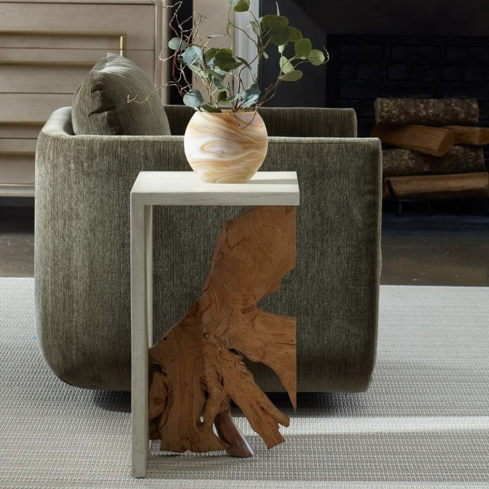 Decorative side table with a natural wood design next to a textured armchair in a room with a fireplace.