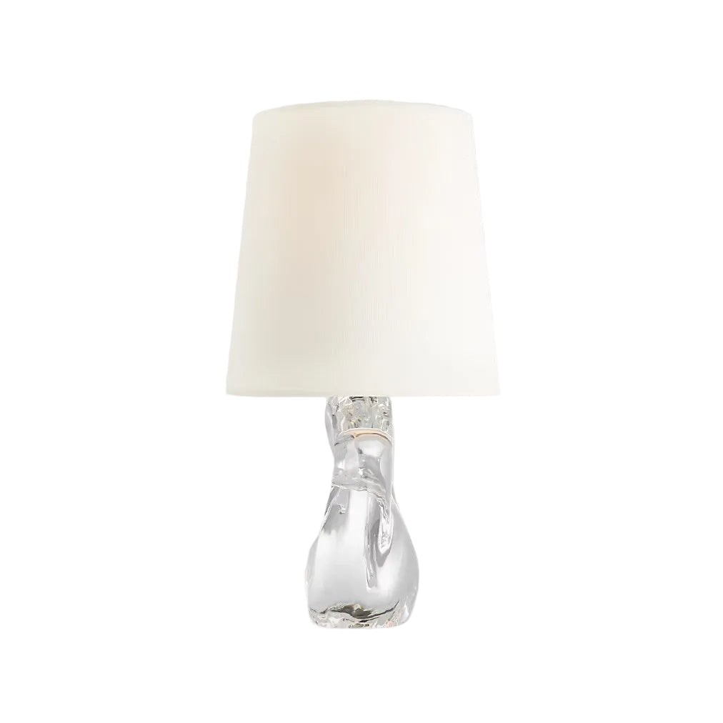 Table lamp with a clear glass base and white fabric shade on a light gray background