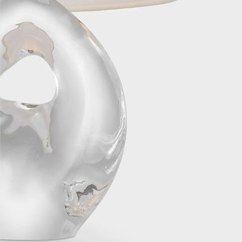 Close-up of a decorative glass lamp with a white base on a light gray background