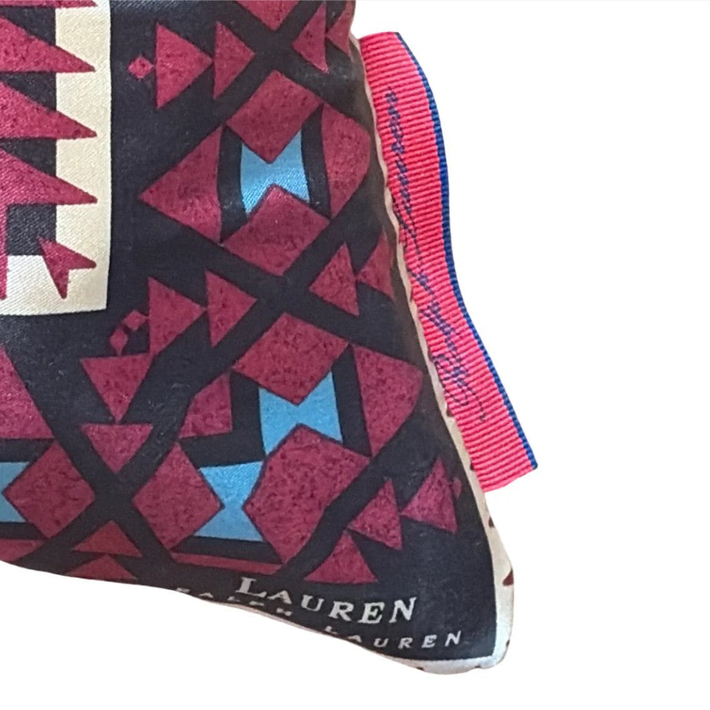A close-up of a vintage Michael Lauren clutch or pouch featuring a geometric pattern in burgundy, light blue, and cream on a black background, with a pink and blue striped ribbon closure.