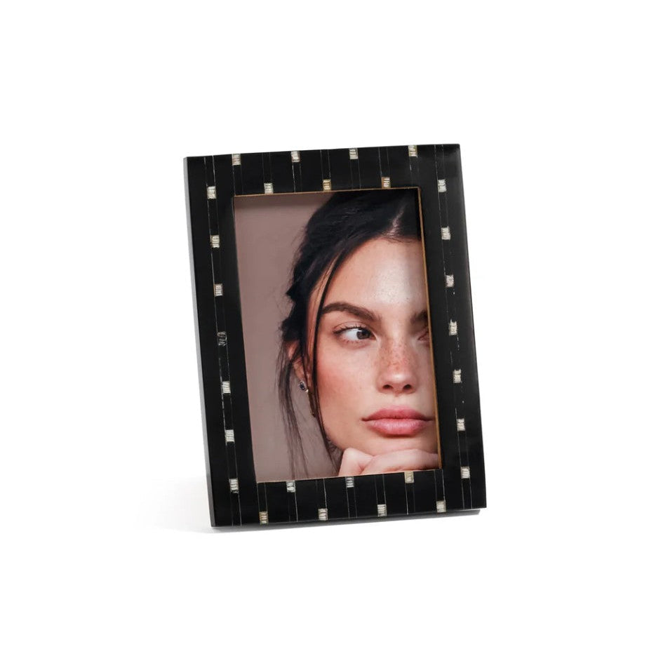 A black picture frame with a geometric pattern of small white and gold square accents around the border, holding a portrait photo of a woman, shown on a clean white background.