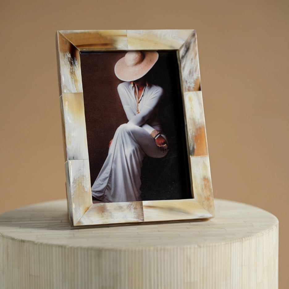 Decorative photo frame with a portrait of a person wearing a hat on a wooden pedestal.