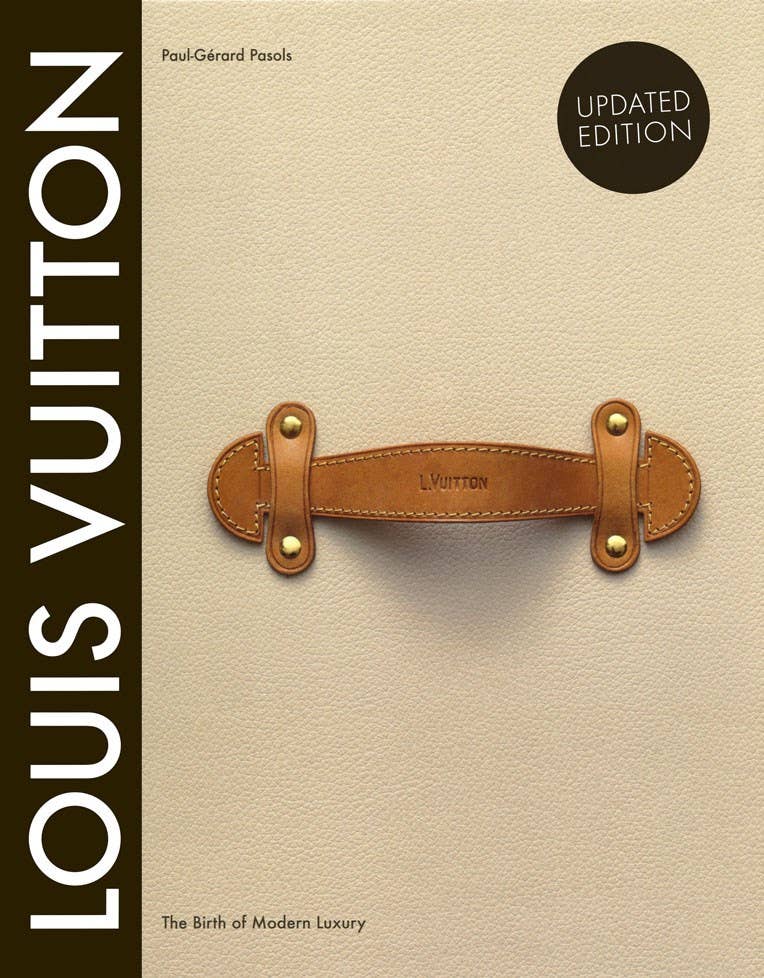 Book cover of 'Louis Vuitton: The Birth of Modern Luxury' with a brown leather tag on a beige background.