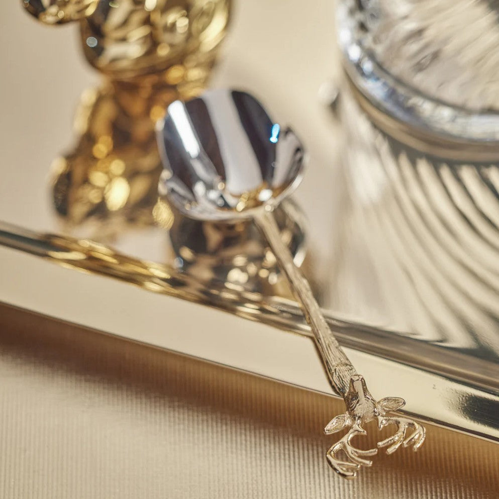 Gold and silver spoon with decorative handle on a reflective surface